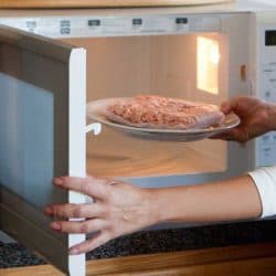 Woman cooking in the kitchen using microwave, Can Melamine Go In The Microwave?