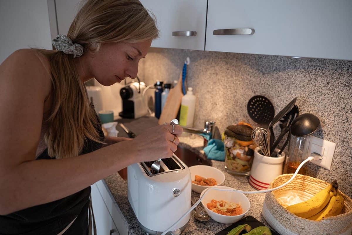 Woman using a fork to unblock faulty read toaster