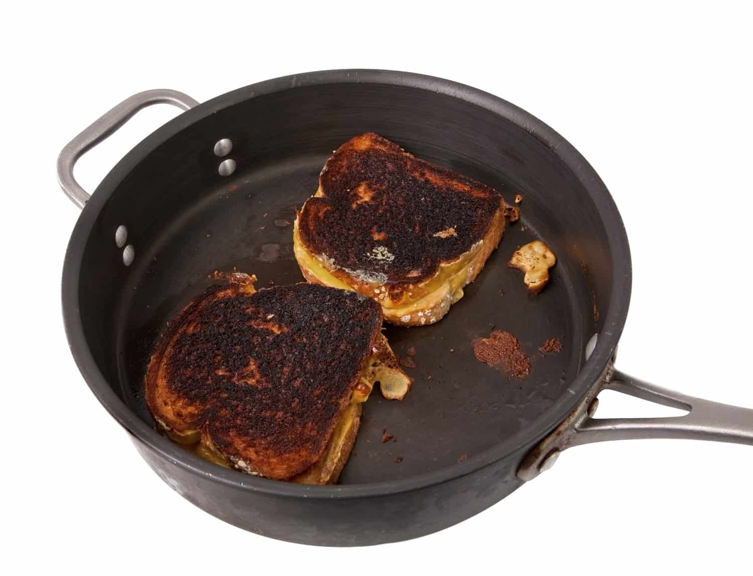 a frying pan with two burnt grilled cheese sandwiches