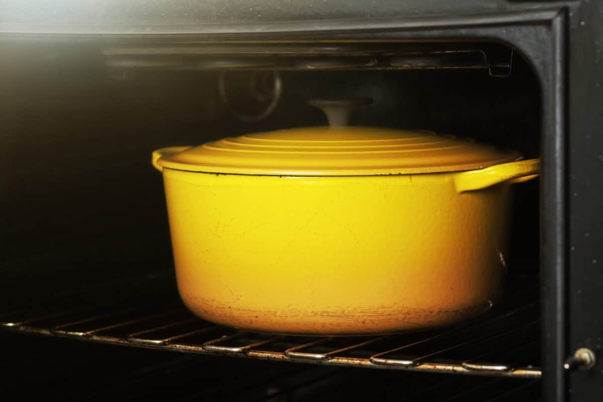 A bright yellow enamel casserole dish sits on a shelf in the oven.