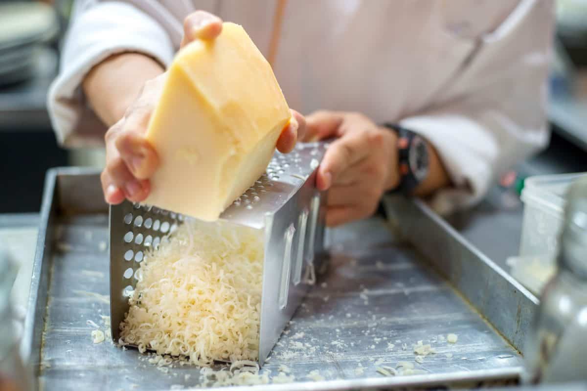 A chef grating a huge chunk of cheese