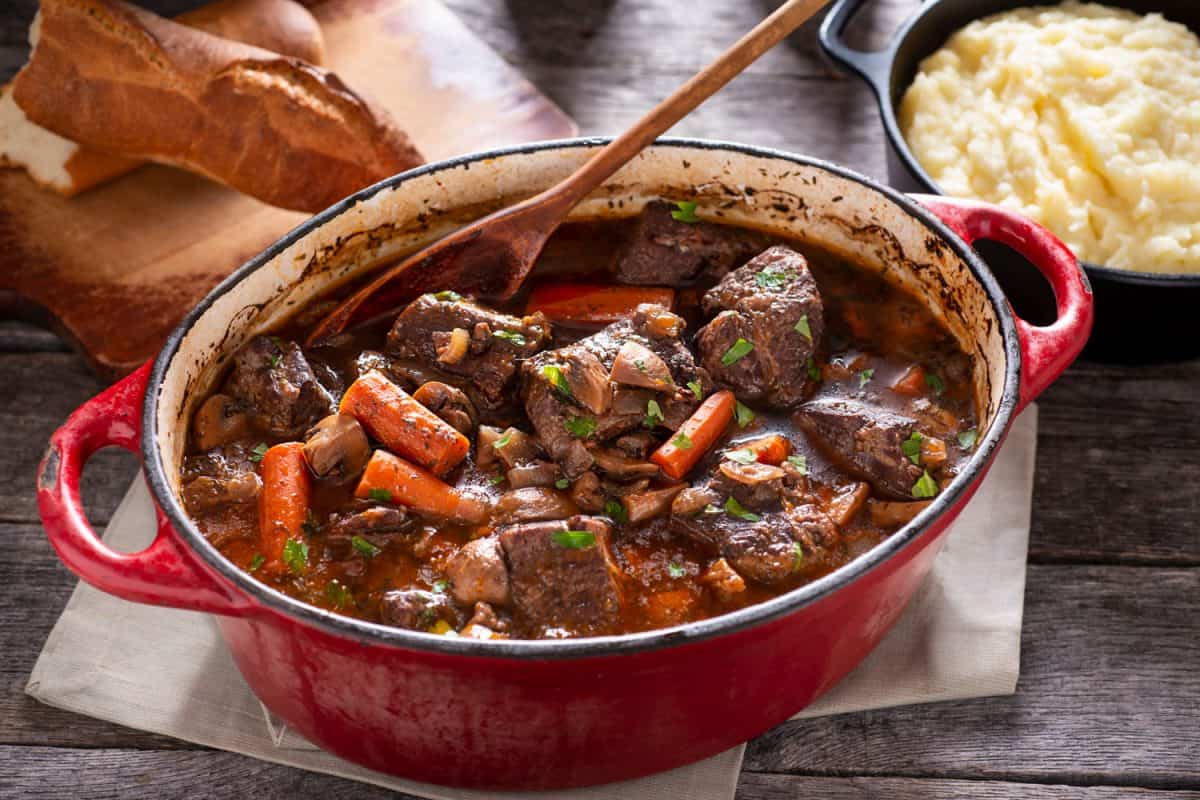 A delicious and savory beef bourguignon in a red enamel dutch oven