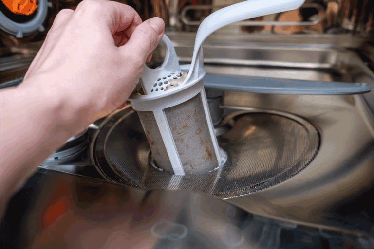 A hand taking out a dirty drain filter of dishwashing machine. Do Dishwashers Only Drain When On