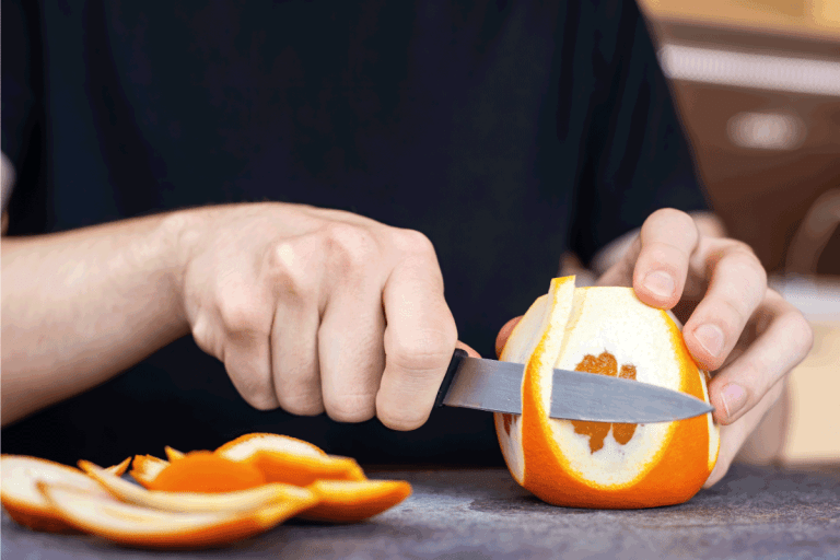 A man peeling an orange using a knife on a cooking board. How Much Does A Paring Knife Cost
