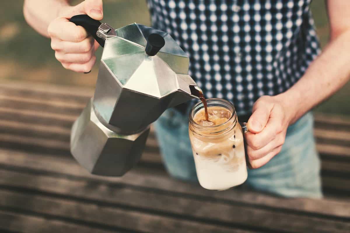 A man pouring coffee from a coffee maker to a jar with milk and ice