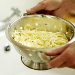 A man preparing and rinsing his pasta on a stainless strainer, Should You Rinse Pasta For Mac And Cheese?