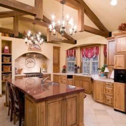 A rustic interior kitchen with bright chandeliers and oak cabinets matching the exposed ceiling membrane, 17 Rustic Kitchen Cabinets Ideas You Should See