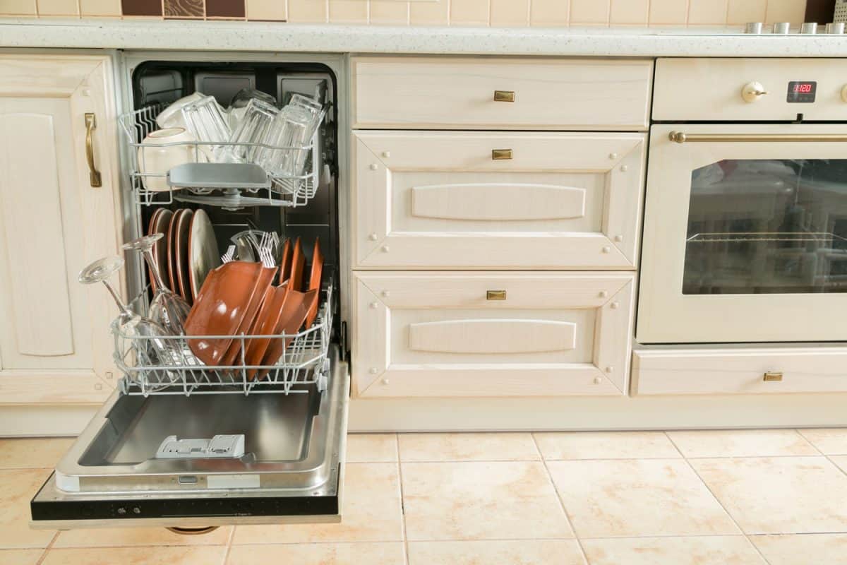 An opened dishwasher with lots of plates and glasses