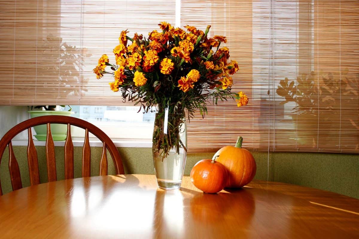 Autumn flowers in a vase and pumpkins on a dining table