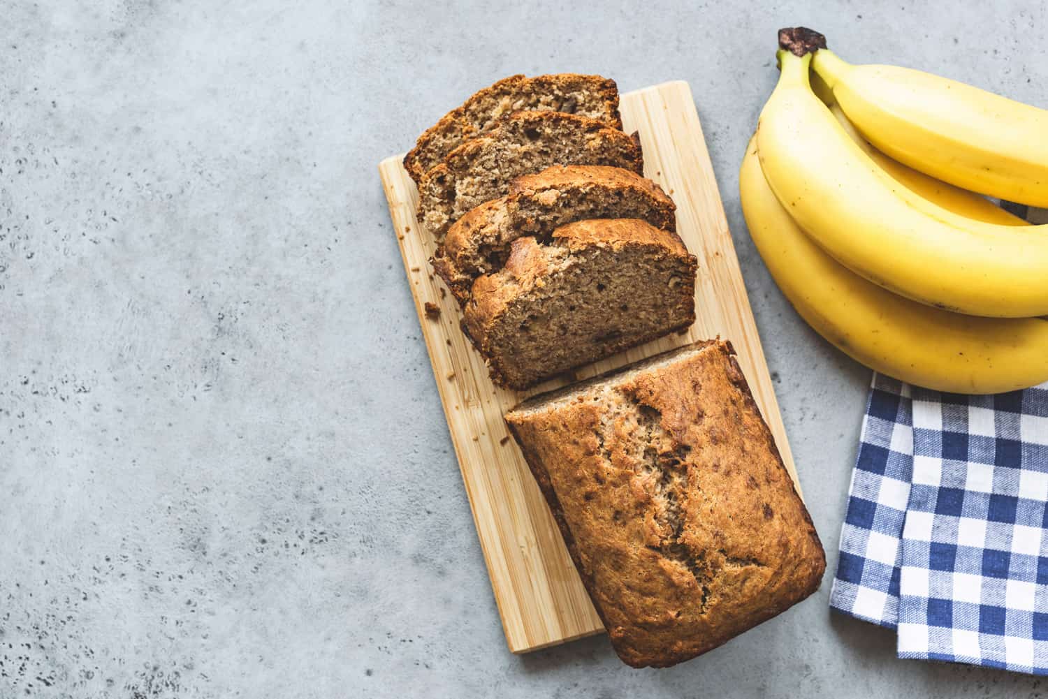 Banana bread loaf with almond nuts sliced on grey concrete background. Table top view and copy space