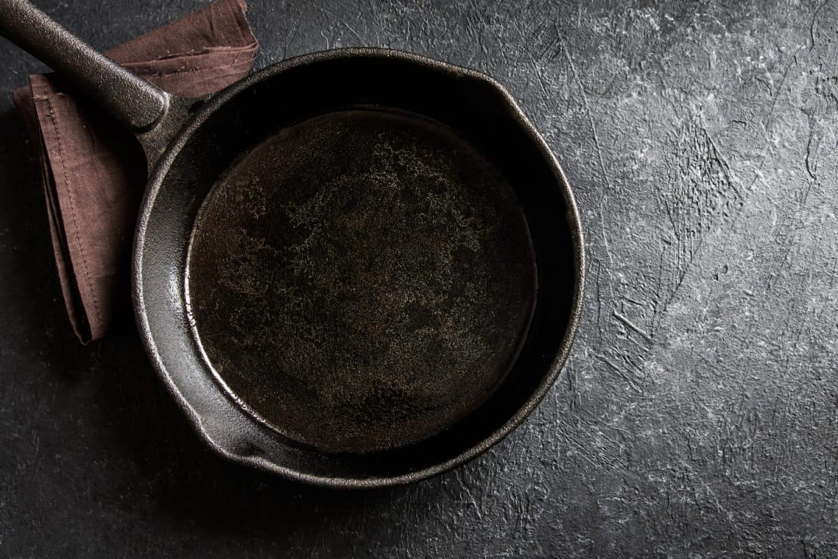 Cast iron pan on rustic black stone background close up - empty black frying pan frying skillet 