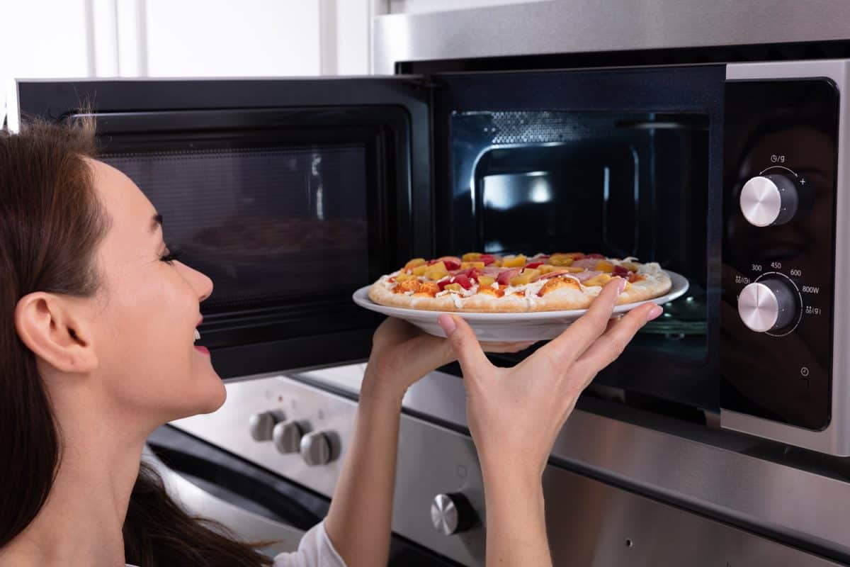 Close-up Of A Happy Woman Baking Pizza In Microwave Oven