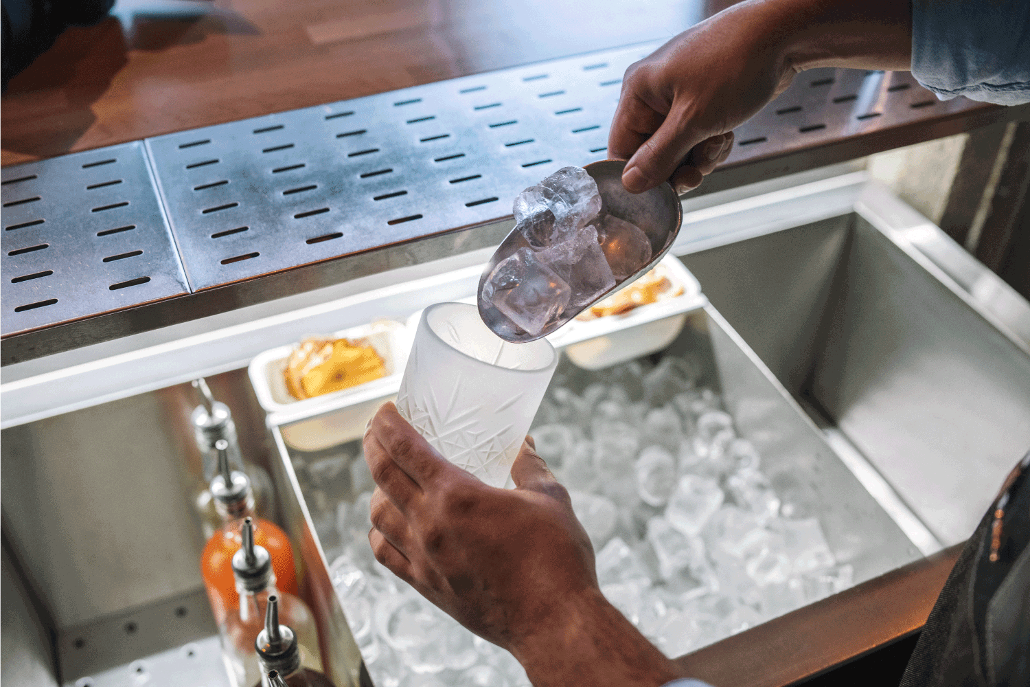 Close-up of bartender hands putting ice in a glass