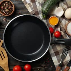 Composition with ingredients for cooking on wooden background with cast iron pan, Should You Season Staub Cast Iron?