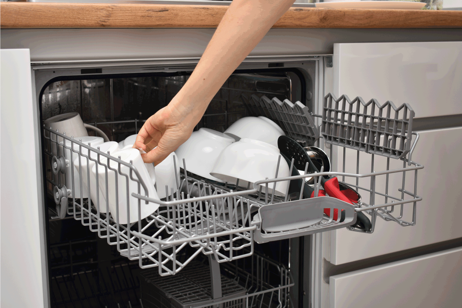Cropped shot of person using dishwasher in modern kitchen