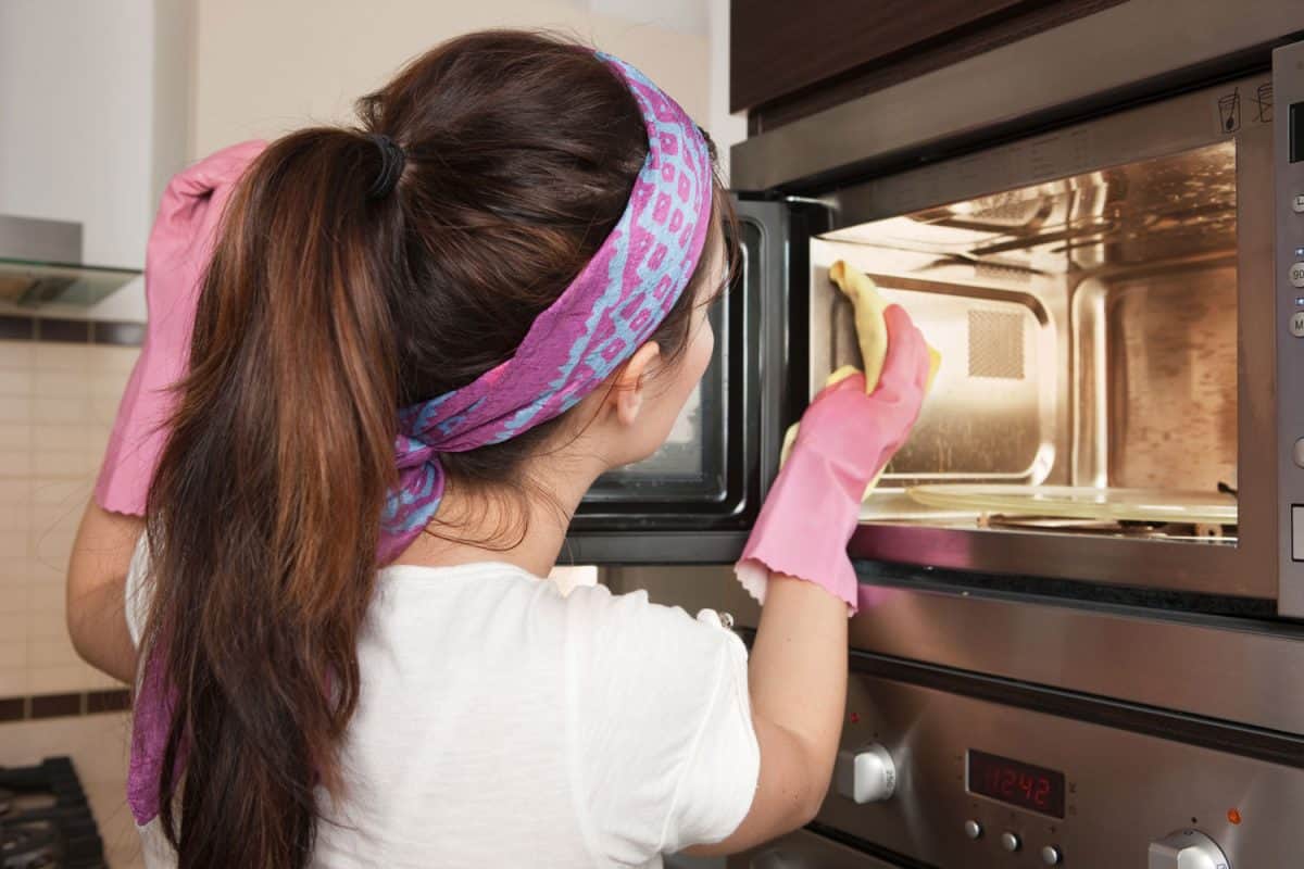 Girl cleaning oven in the kitchen, How To Clean A Microwave's Grease Filter