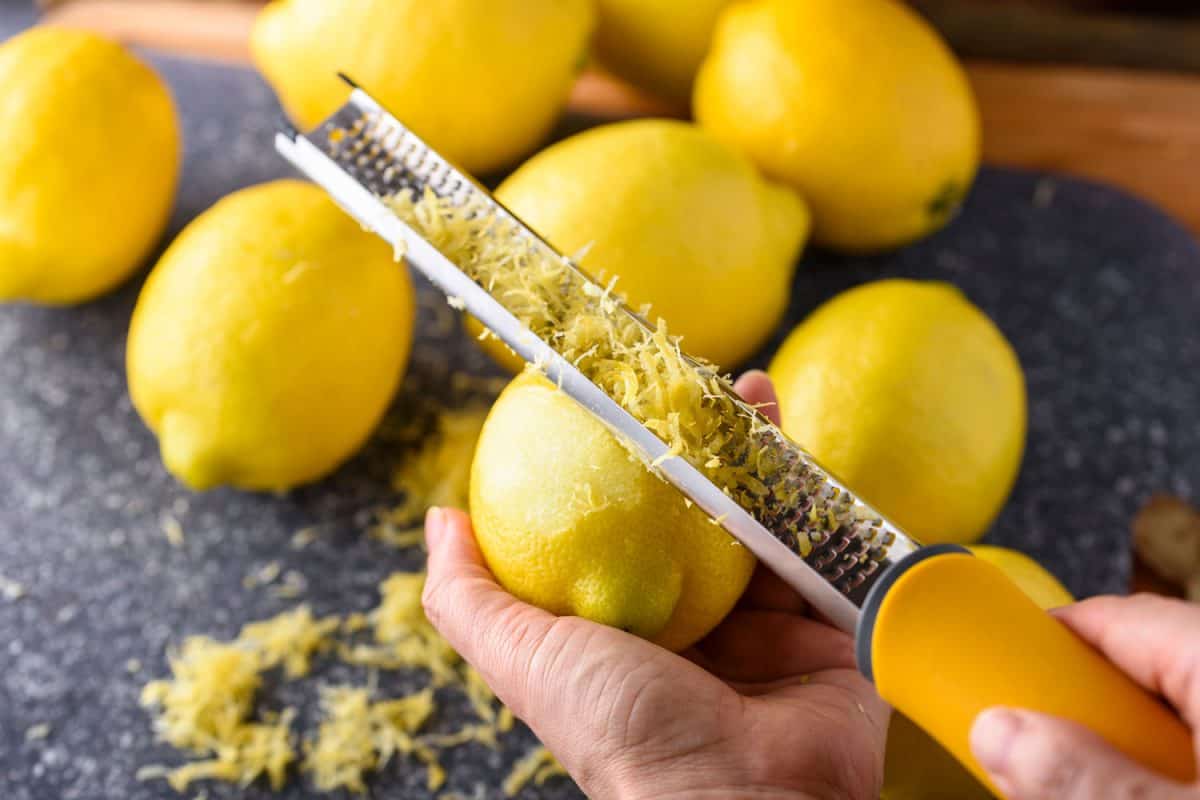 Hand zesting lemon using a grater, How To Zest A Lemon [5 Ways, Inc. Without A Grater]