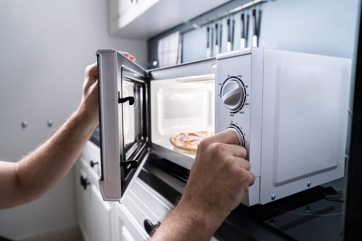 Human Hand Baking Pizza In Microwave Oven