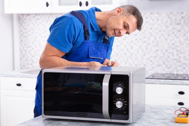 Man repairing microwave oven, Microwave Runs But Not Heating Up - What To Do?