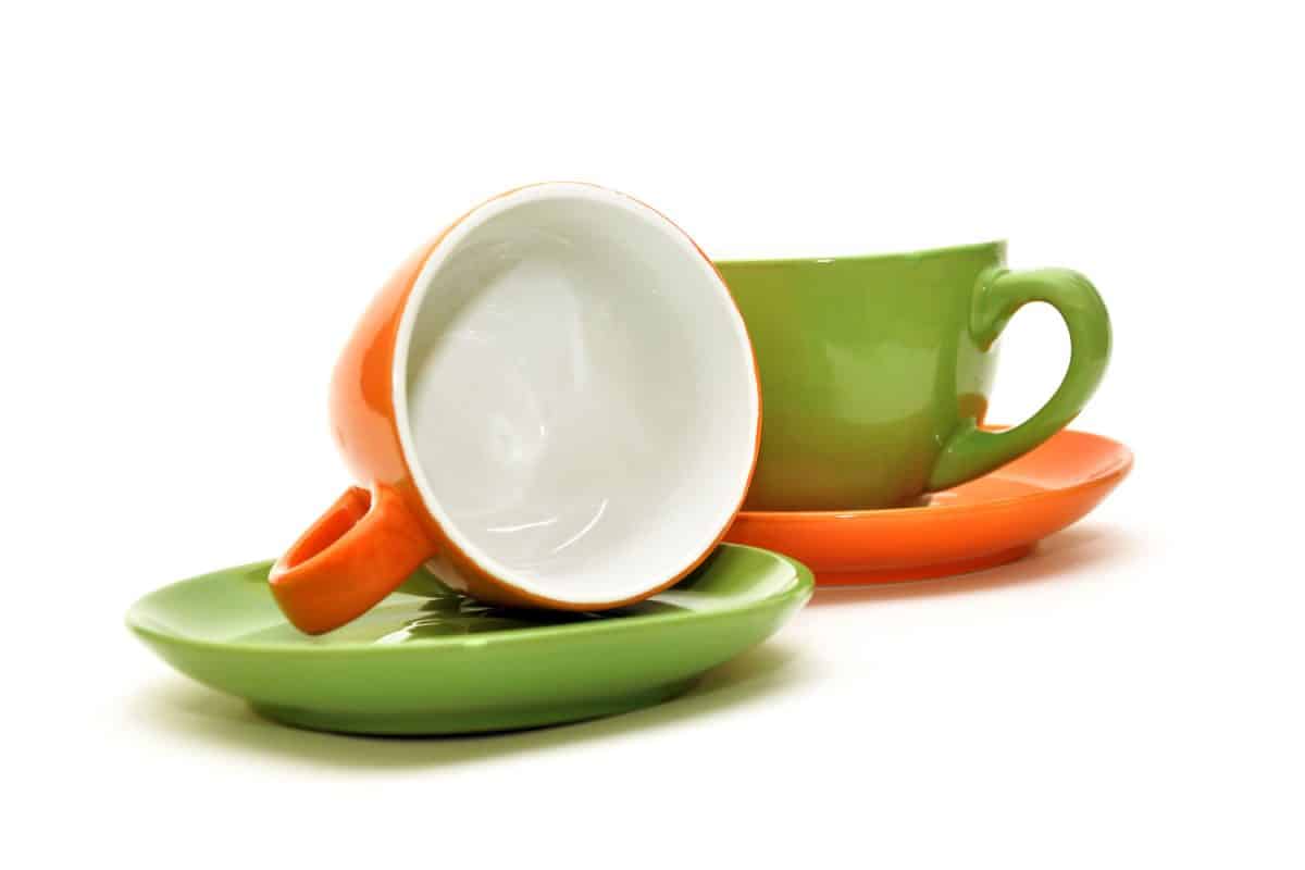 Orange and yellow green colored mugs and coasters on a white background