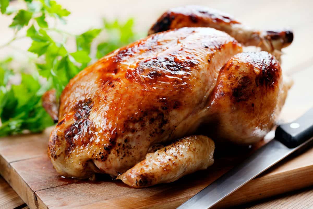 Oven baked whole chicken on a chopping board