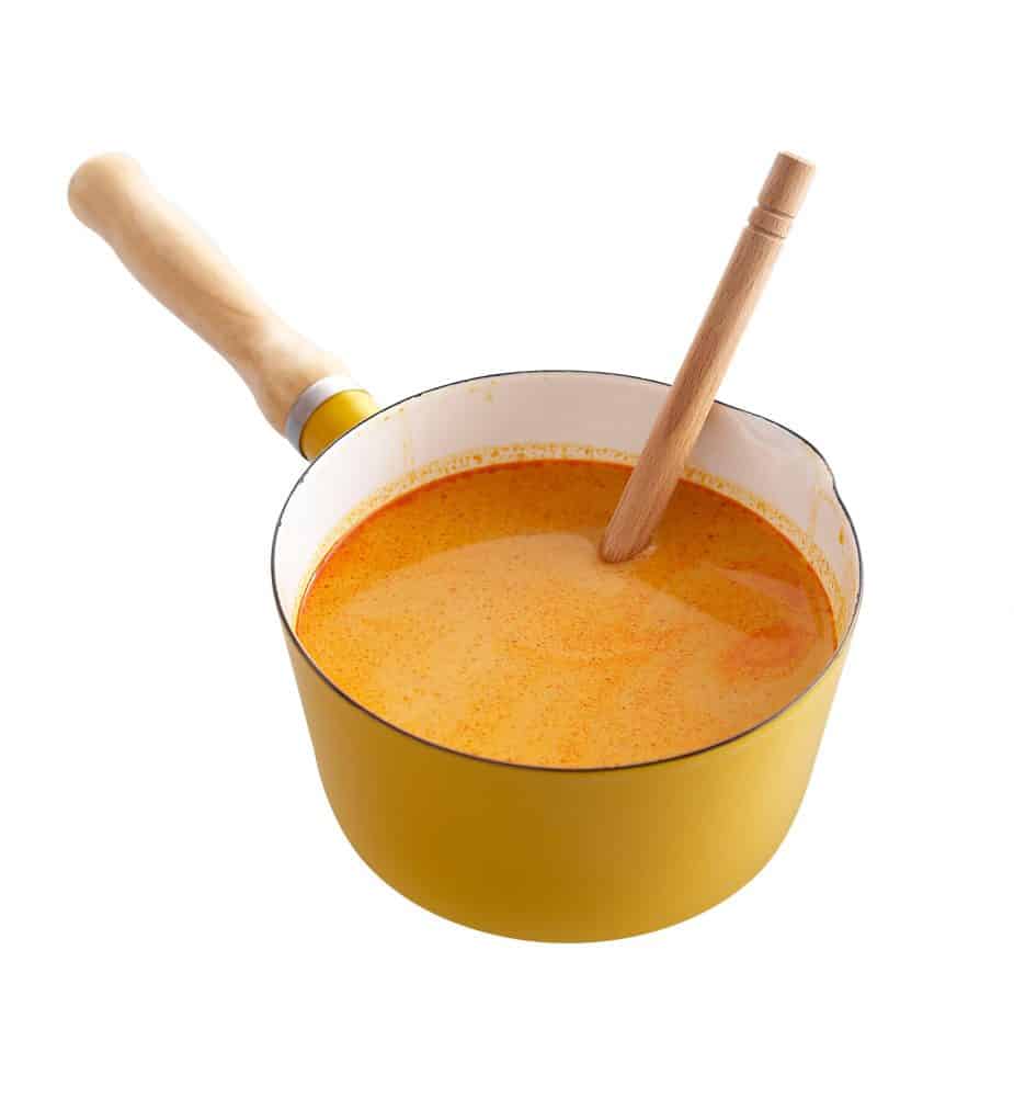 Red curry in yellow enamel pot isolated on white background