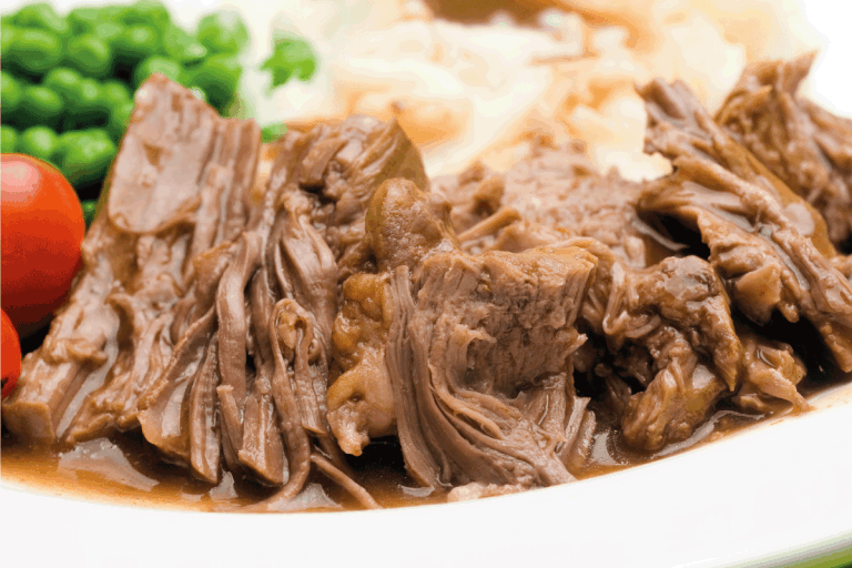 Sliced pot roast dinner on a white plate close up. How Long Should You Cook A Pot Roast