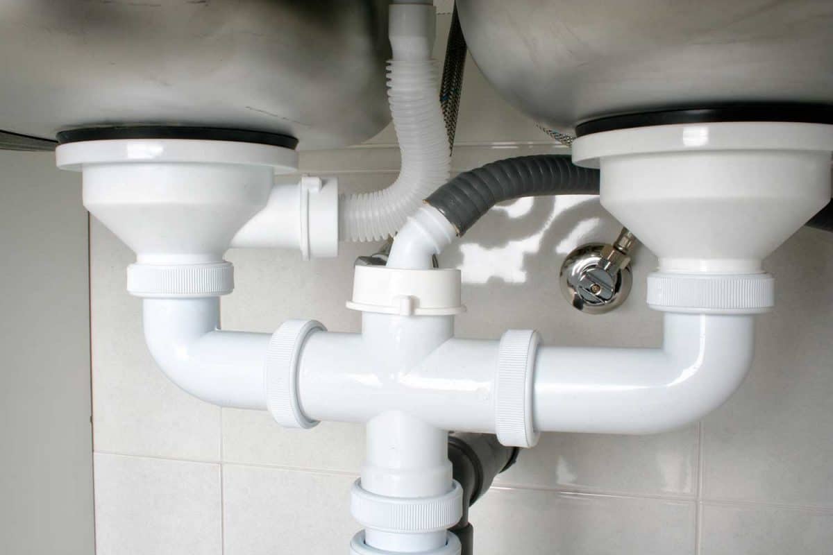 View of the drain pipes of a kitchen sink with dishwasher connection