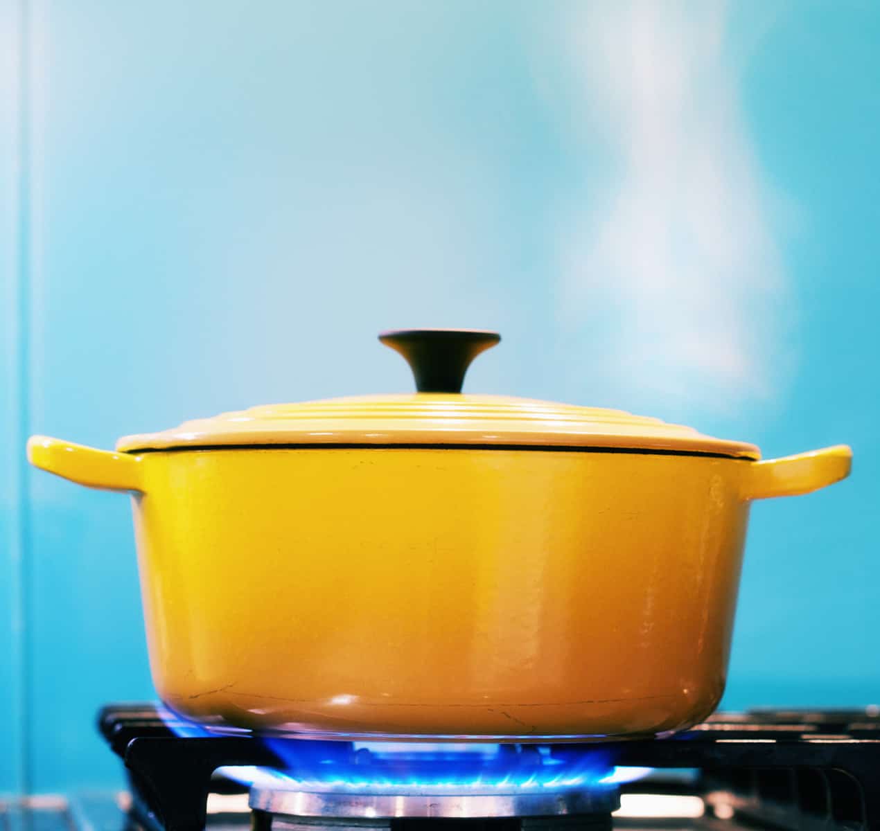 Yellow lidded pot steaming on lit gas stove