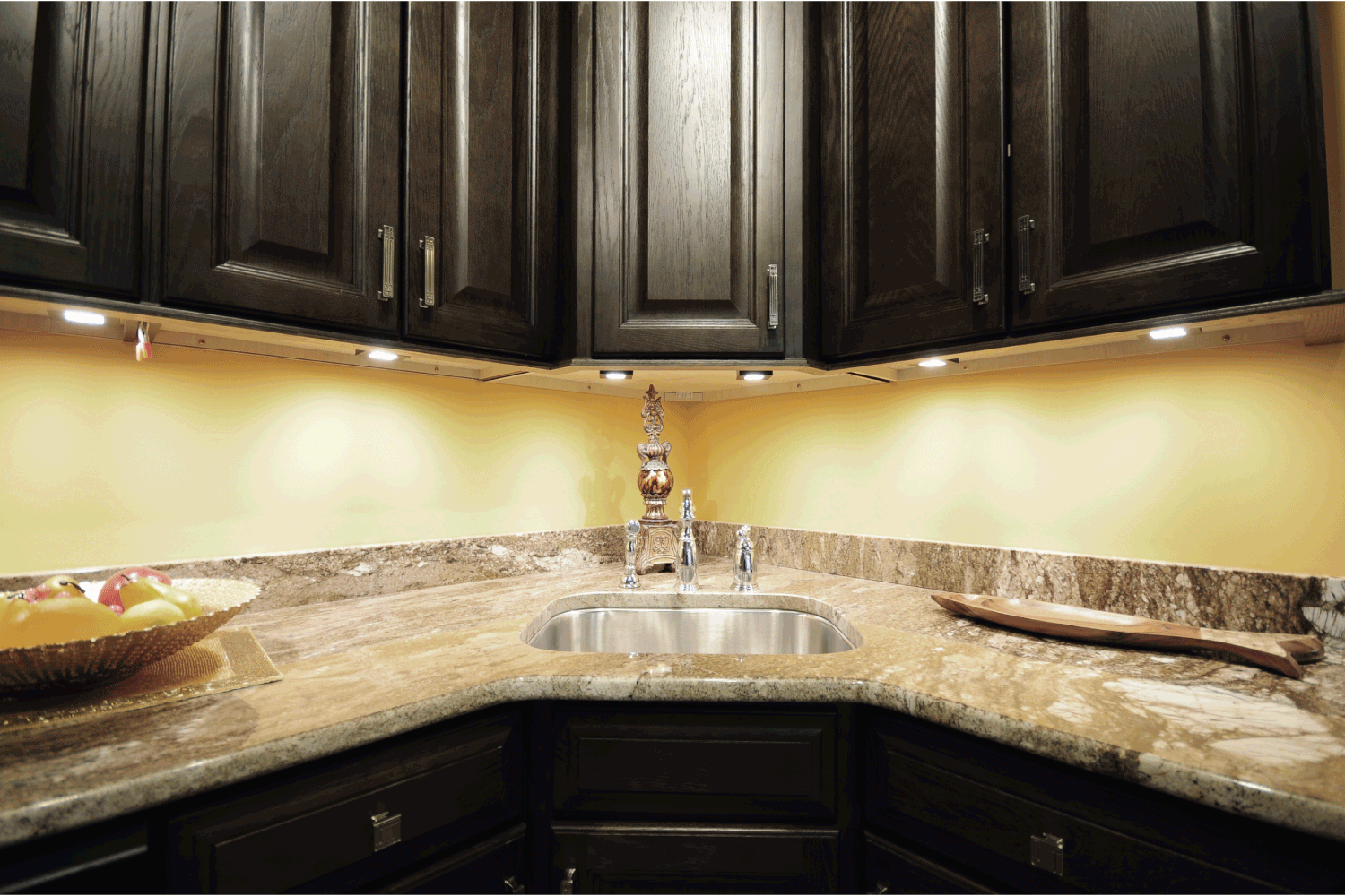 dark kitchen cabinets above granite kitchen sink with down lights