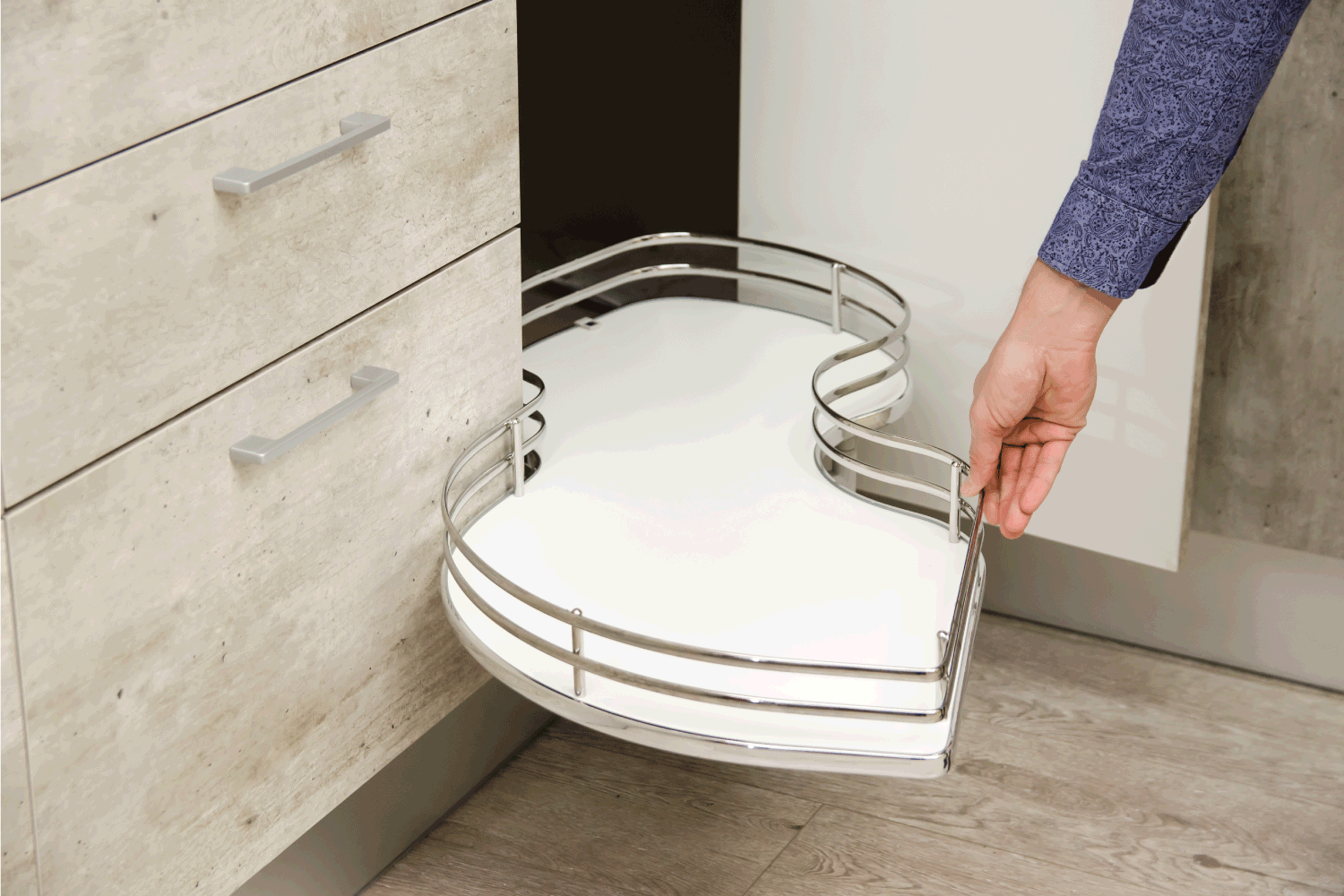 an pulls a kitchen carousel out from the bottom drawer of a cabinet in a modern kitchen. squiggly drawer