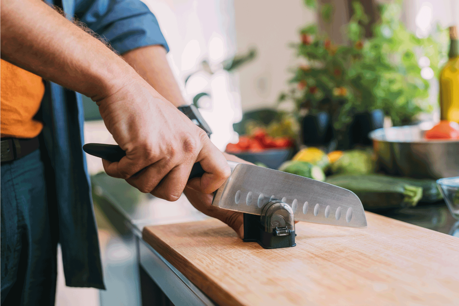man sharpening a knife using a knife sharpener on a cutting board in a kitchen.