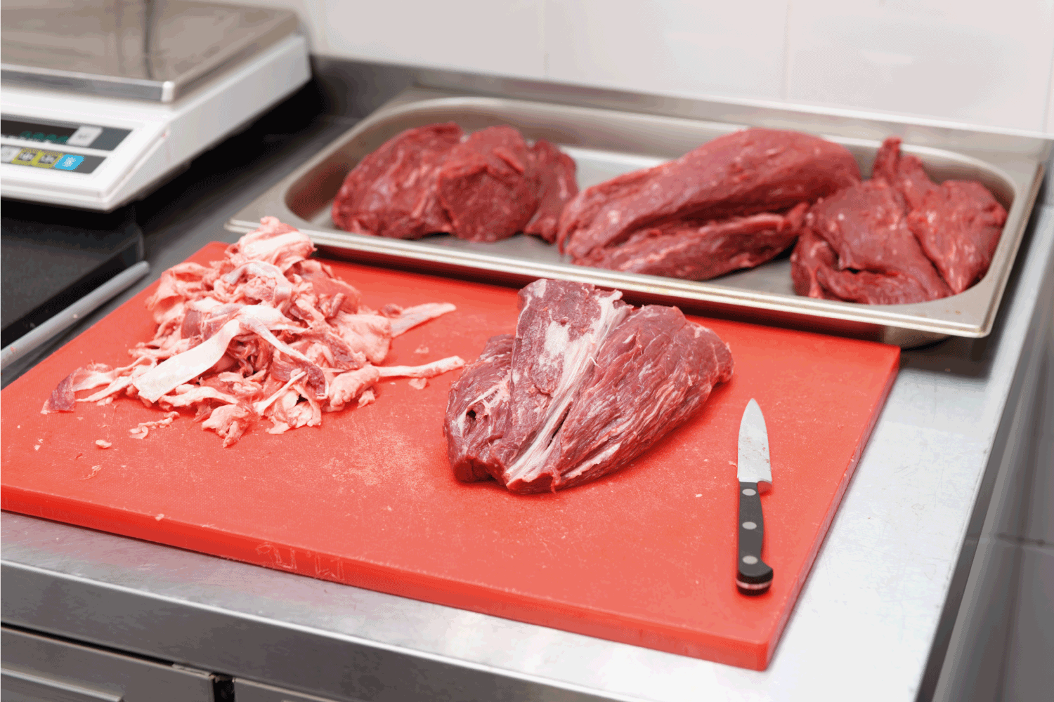 trimming meat fat in a restaurant kitchen with a paring knife