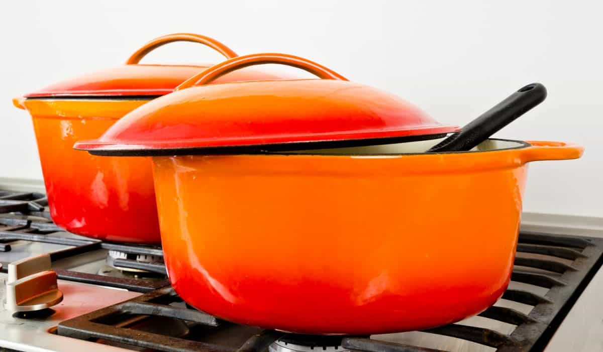 two bright orange pots from cast iron with enamel at an old vintage gas stove