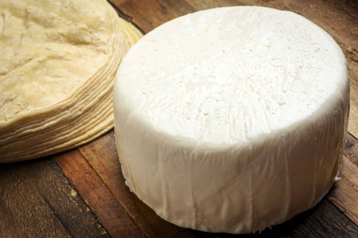 A big queso fresco with tortilla chips on the table