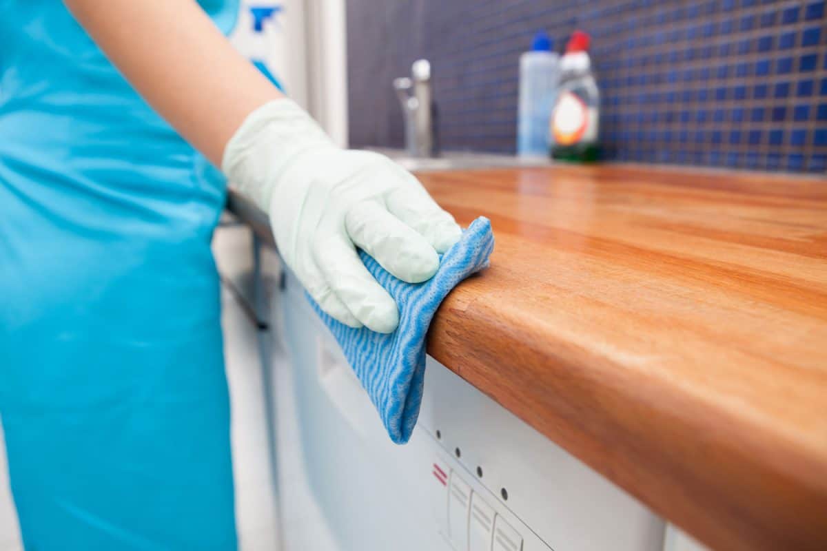 A maid cleaning the wooden kitchen