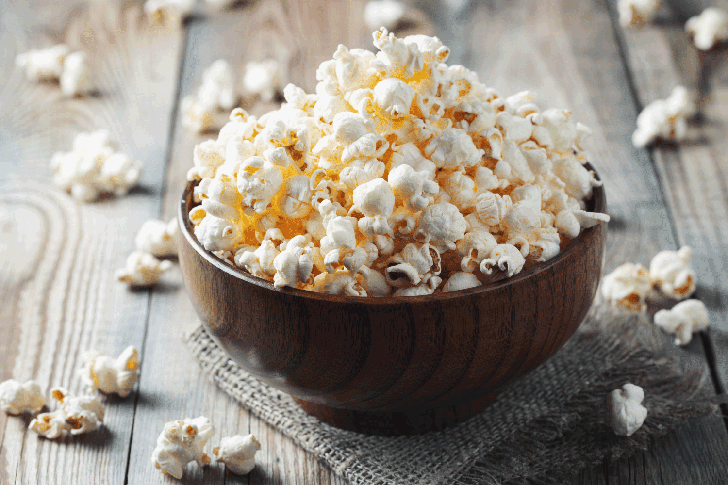 A wooden bowl of salted popcorn at the old wooden table