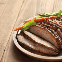 Barbecue beef brisket in a white plate, wooden table. At What Temperature Should You Cook A Roast