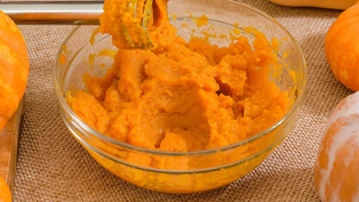 Fresh pumpkin puree in a glass bowl close up on rustic background. Making pumpkin puree from scratch, step by step recipe