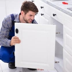 Handyman fitting a new cabinet door under the kitchen worktop, How To Replace Kitchen Cabinets Doors