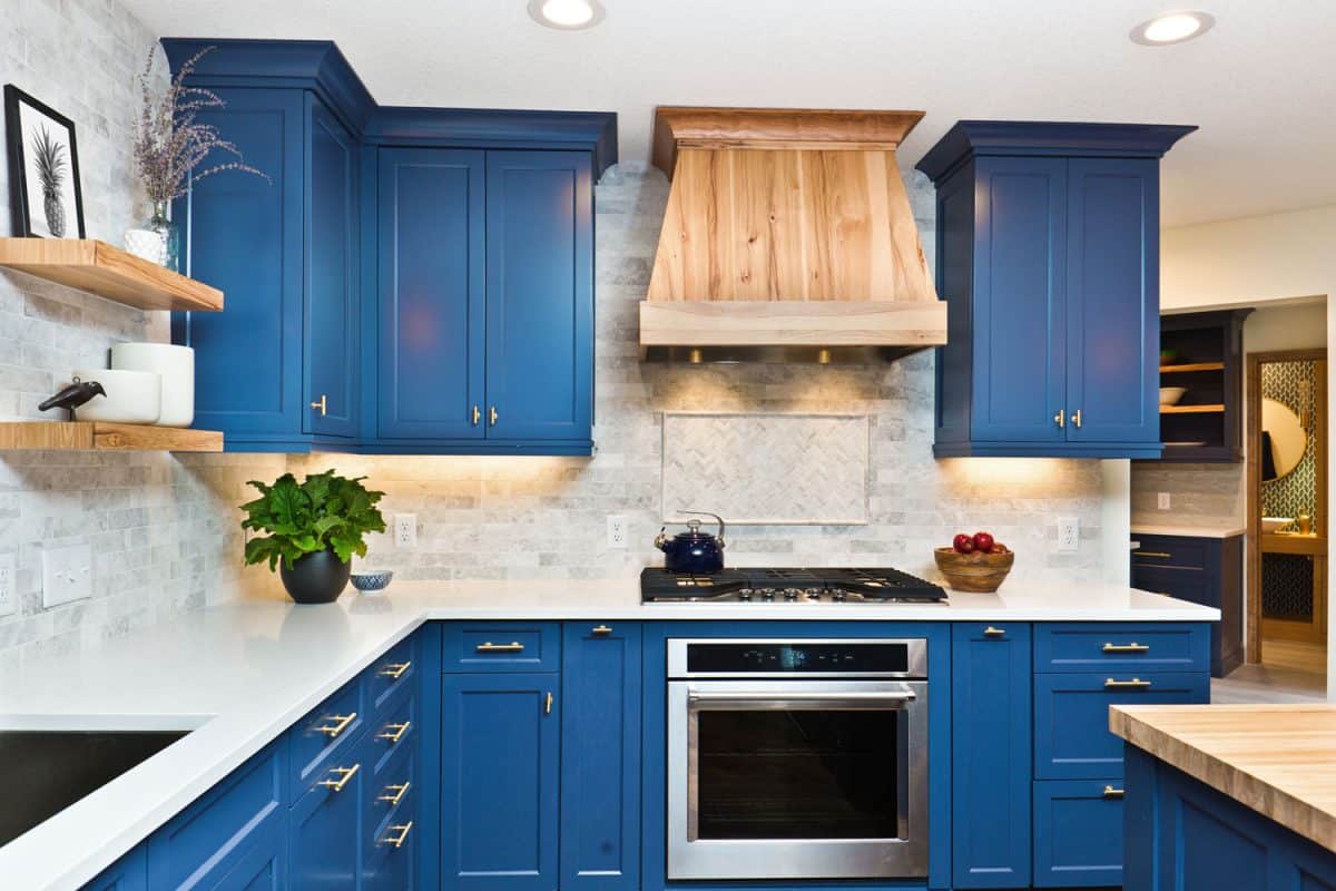 Interior of a modern kitchen with blue cabinets and a white kitchen countertop