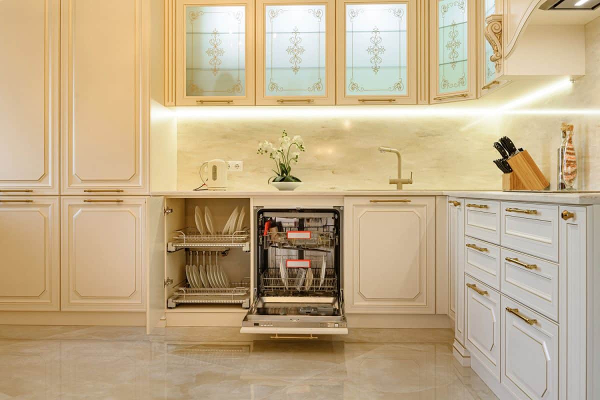 Large luxury beige and gold classic kitchen interior with furniture in Provence style, cabinet door and dishwasher are open, Can You Stop A Dishwasher Mid Cycle?