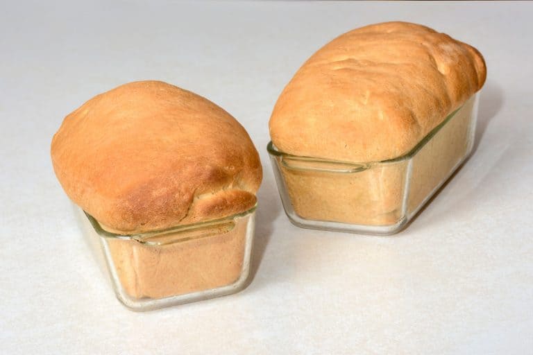 Beautifuly baken bread loafs with golden tops in glass loaf pan, Can You Bake Bread In A Glass Loaf Pan? Does It Take Longer?