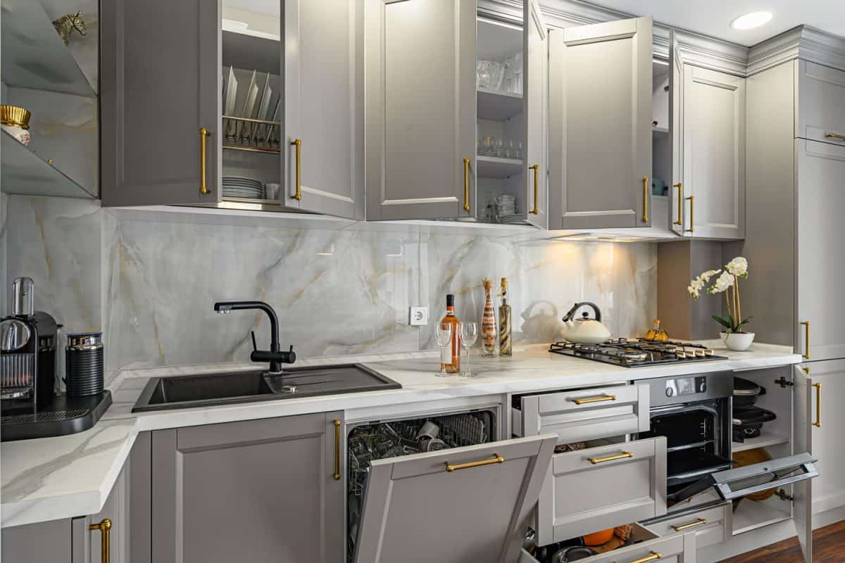 Luxurious interior of a modern contemporary kitchen with gray cabinets incorporated with gold handles and white countertop