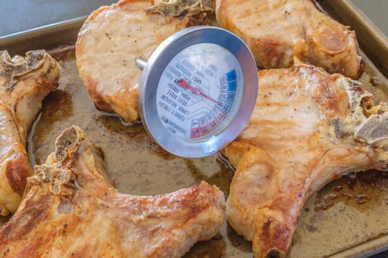 Thermometer taking the temperature of thick pork chops, At What Temperature Should You Cook Pork Chops?