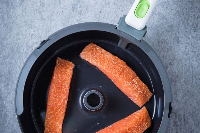 Three pieces of raw salmon in the air fryer at the center with a grey background, Can You Dehydrate In The Cuisinart Air Fryer? [With Tips On How To Do So]