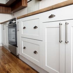 White kitchen cabinets with stainless steel handles and cup handles, Where Should Kitchen Cabinet Knobs And Handles Be Placed?