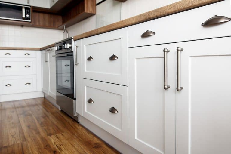 White kitchen cabinets with stainless steel handles and cup handles, Where Should Kitchen Cabinet Knobs And Handles Be Placed?