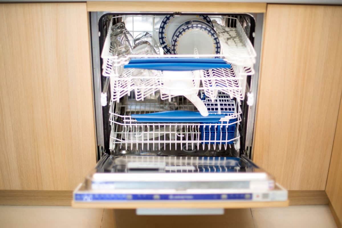 A flushed dishwasher containing lots of newly washed dishes