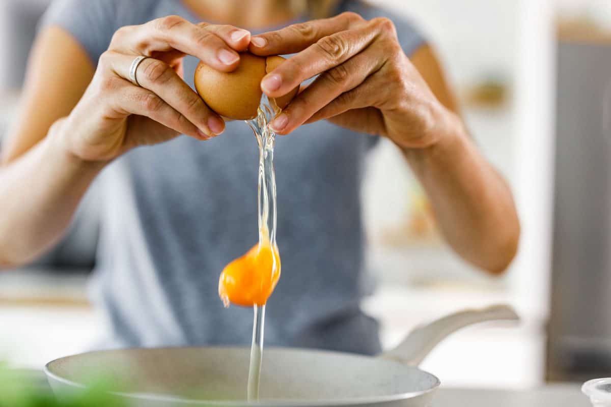 A focused photo of a womans hands cracking eggs